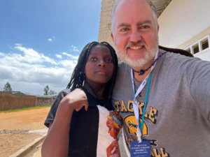 Close-up selfie of H.K. smiling with a young girl during outdoor missions in Africa.